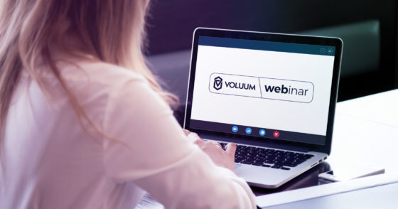 a person sitting in front of a notebook that has "Voluum webinars" sign displayed on it